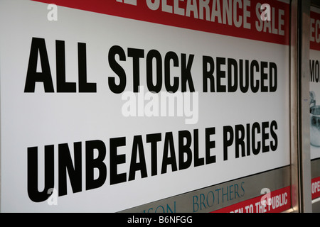 Sign across a full shop window on a high street in Belfast UK all stock reduced unbeatable prices special clearance sale Stock Photo