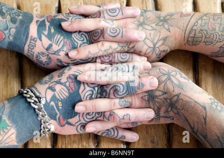 The entwined hands of a married couple who both have extensive tattoos Stock Photo