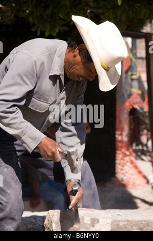 Laborer wearing a hat doing hammer and chisel construction in San Miguel de Allende, Mexico. Stock Photo