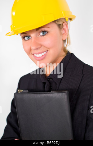 A beautiful young woman dressed in a suit and hard hat carrying a black leather folder Stock Photo