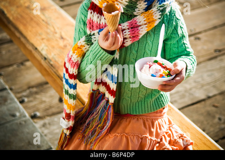 A girl, 4-5 years, enjoys a bowl of ice cream and m&m's on a cold day. Stock Photo