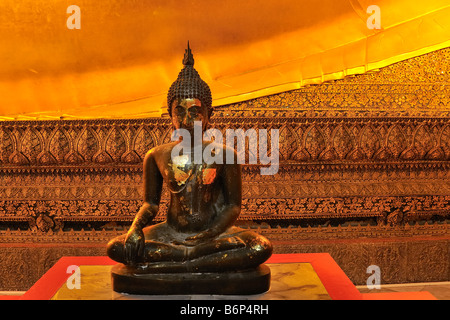 Small Buddha image beside the reclining Buddha in Wat Pho temple, Bangkok, Thailand. Stock Photo