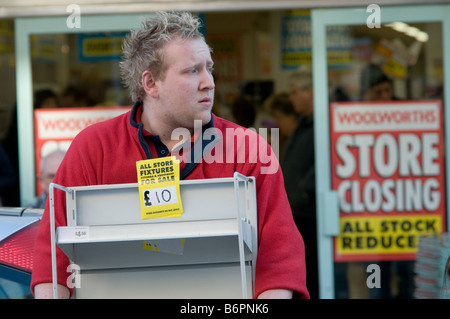 woolworths store closing down sale; member of staff carrying out items of fixtures and fittings that were sold off. Stock Photo