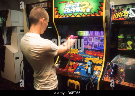 Teen boy plays arcade shooting game. Stock Photo