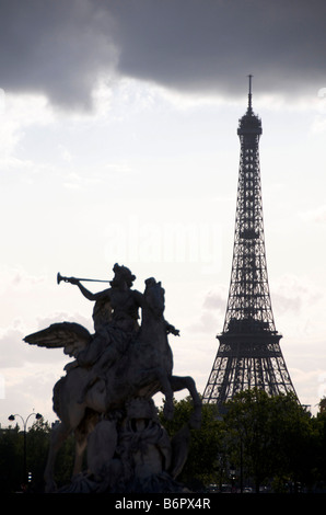 Eiffel tower silhouetted in Paris, France with statue of Renommée, (fame of the king), riding Pegasus in the Tuileries gardens. Stock Photo