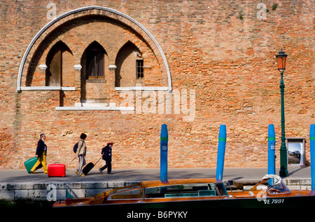 Venice, Veneto, Italy. Family taking luggage to railway station, passing distinctive window Stock Photo