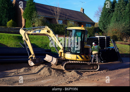 Road digger tractor working on road after laying electrical cabling Stock Photo