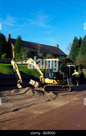 Road digger tractor working on road after laying electrical cabling Stock Photo