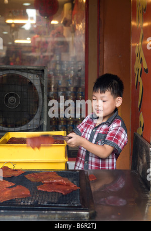 Young boy cooking bakkwa or rougan Stock Photo