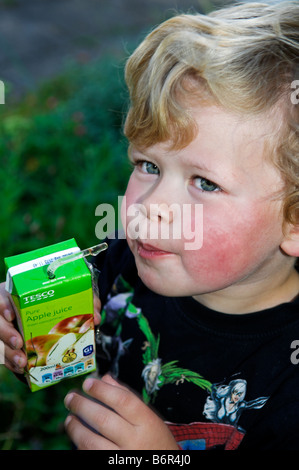 Four year old boy drinking juice from carton with a straw Stock Photo