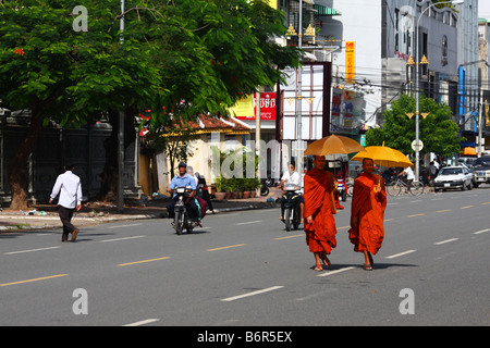 Two (2) buddhist monks in saffron robes walking with umbrellas in the streets of Phnom Penh, Cambodia Stock Photo