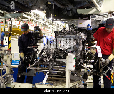 Workers at Toyota Final Assembly production line prepare the engine for installation to the chassis of a Toyota Avensis car Stock Photo