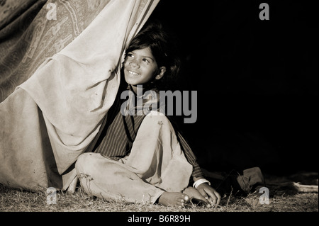 Poor nomadic indian girl sitting inside her tent home. Andhra Pradesh, India.  Sepia tone Stock Photo