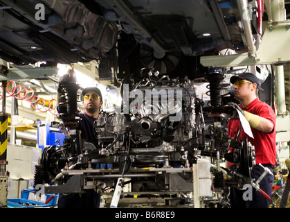 Workers at Toyota Final Assembly production line prepare the engine for installation to the chassis of a Toyota Avensis car Stock Photo