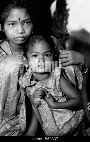 Poor nomadic indian girl and her baby sister. Andhra Pradesh, India. Black and White Stock Photo