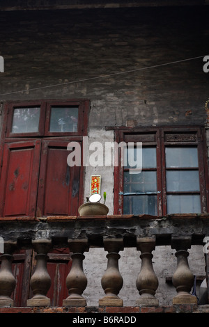 The back of an old cantonese house balcony with a plant in a bowl seen Also you can see the traditional mirror on the door. Stock Photo