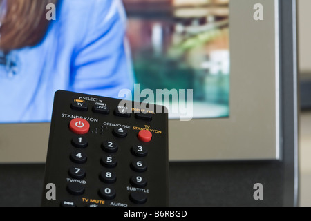 Britain UK TV remote control with red standby button and television screen transmitting behind Stock Photo