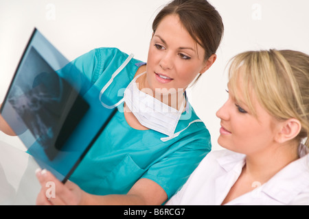 A female doctor and her nursing colleague examining an X ray of a human skull Stock Photo