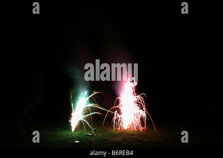 small family firework display in personal space on lawn in darkness in landscape horizontal format including the ground Stock Photo