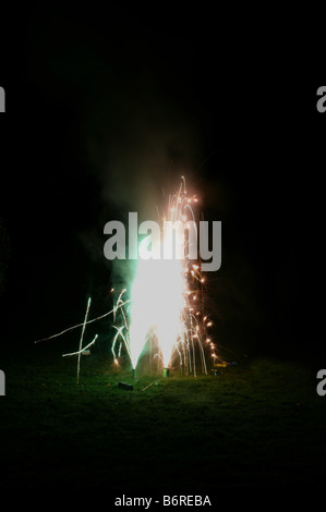 small family firework display in personal space on lawn in darkness in portrait upright format including the ground Stock Photo