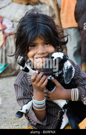 Poor nomadic Indian girl playing with a baby goat. Andhra Pradesh, India Stock Photo