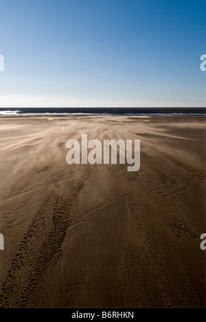 Wind blowing sand across the empty beach at Dunraven Bay in South Wales. Stock Photo