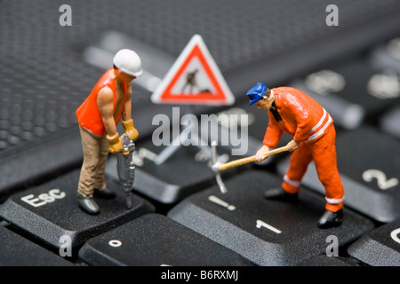 Miniature figures working on a computer keyboard. Stock Photo