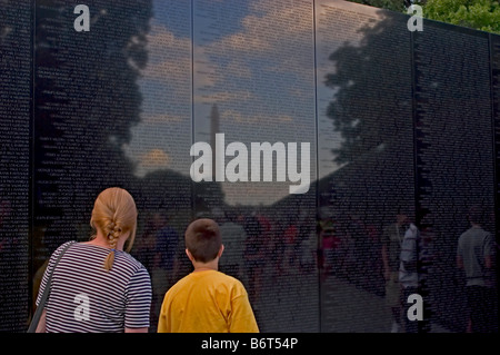 Mother and son read names on Vietnam Memorial, Washington, DC USA Washington Monument appears in reflection with soldier names. Stock Photo