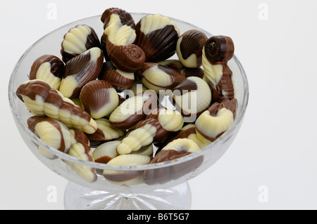 Belgian seashell shaped black white and milk chocolates in a crystal bowl on white background Stock Photo