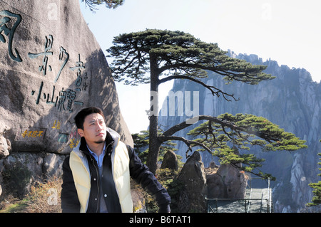 Chinese tourist posing by the famous 'Welcoming Guest Pine', Huangshan, Yellow Mountain, China. Even Chairman Mao posed here. Stock Photo