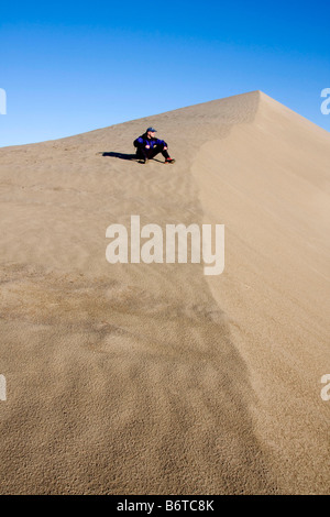 A hiker rests on a sand dune above the White Bluffs of the Hanford Reach along the Columbia River Washington Stock Photo