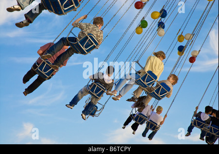 Kids having fun on a chaining roundabout under blue sky at a local spring fair in Munich April 2007 Stock Photo