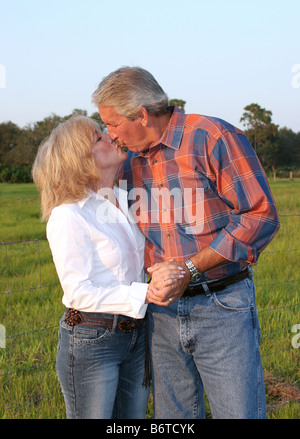 a good looking mature couple kissing in the late afternoon sun Stock Photo
