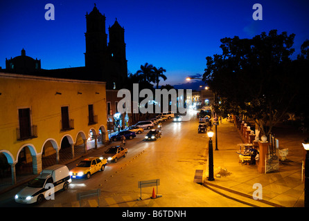 VALLADOLID, Yucatan, Mexico — A nighttime street scene in downtown Valladolid, captured from the balcony of City Hall. The view showcases the colonial architecture and vibrant atmosphere of this historic Yucatecan town. Illuminated by street lights, the scene depicts local life and the charm of Valladolid's central area, with its colorful buildings, pedestrians, and the blend of traditional and modern Mexican culture. Stock Photo