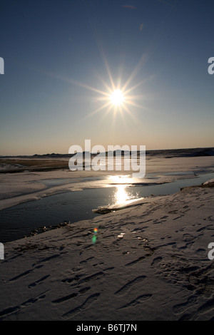 Footprints on melting ice sheet on Lake Michigan near sunset Stock Photo
