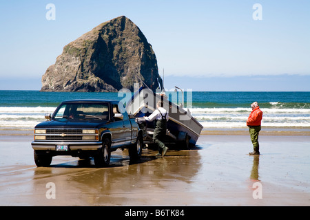 Pacific Dory Fleet boat being loaded up onto truck on the beach at Cape Kiwanda Oregon USA Stock Photo