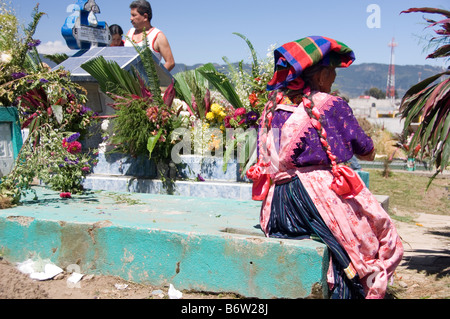 Woman in traditional dress sitting on the grave of one of her relatives on "All Souls Day". Quetzaltenango, Guatemala. Stock Photo