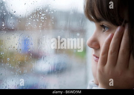 young child looking out of window on rainy day Stock Photo