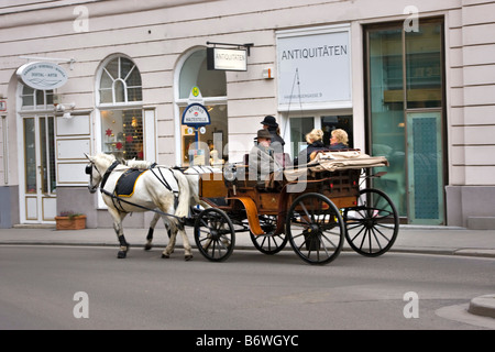 Fiaker in Vienna driving tourists past an antique shop Stock Photo