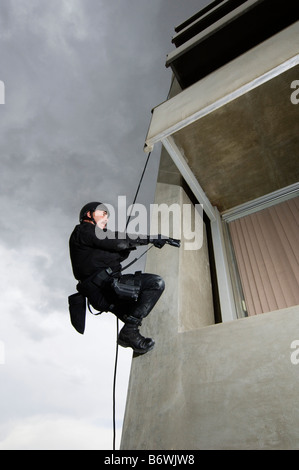 SWAT Team Officer Rappelling and Aiming Gun Stock Photo