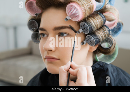 Model in Hair Curlers Having Makeup Applied Stock Photo