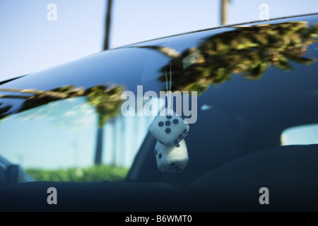 Fuzzy dice hanging from rear view mirror of car Stock Photo