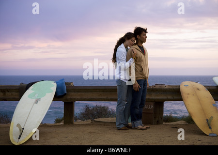couple embrace on cliff overlooking beach Stock Photo