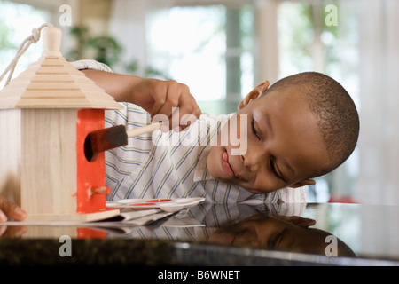 A boy painting a birdhouse Stock Photo