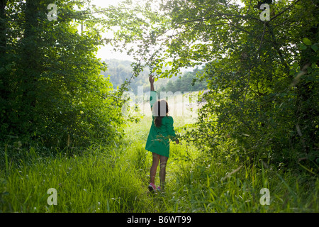 A girl trying to reach for a branch on a tree Stock Photo