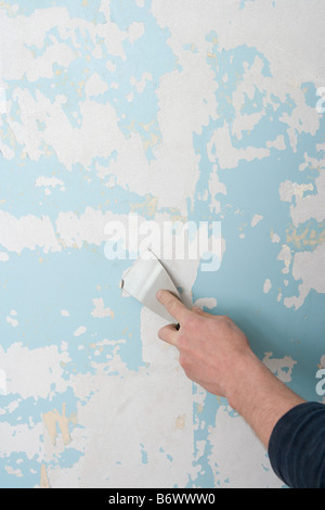 A decorator scraping wallpaper off a wall Stock Photo