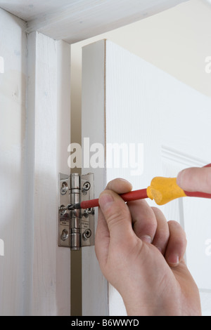 A builder fixing a door to a hinge Stock Photo