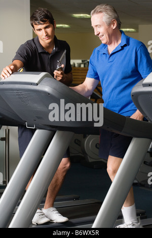 A personal trainer helping a man on a treadmill Stock Photo