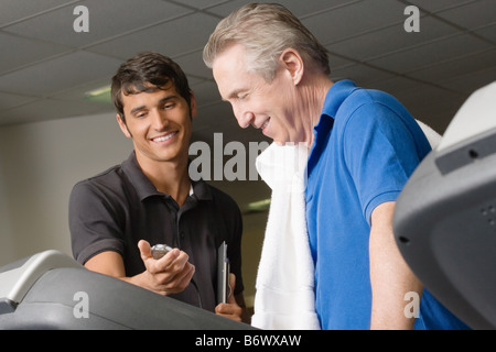 A personal trainer helping a man on a treadmill Stock Photo