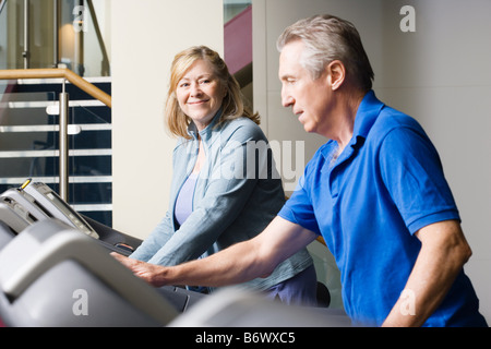 A man and woman using treadmills in the gym Stock Photo